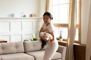 Woman holding and playing with child in living room cooling